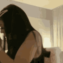 a woman with long black hair is standing in front of a mirror in a bedroom .