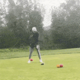 a woman is swinging a golf club on a golf course while holding a golf club .