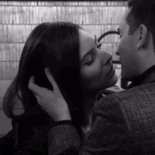 a man and woman are touching each other 's faces in a black and white photo