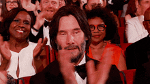 a man in a tuxedo and bow tie is clapping in a crowd of people