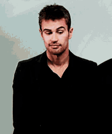 a man in a black jacket and black shirt is making a silly face