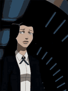 a woman in a suit and tie is standing in front of a clock in a dark room .