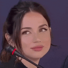 a close up of a woman 's face with a microphone in her hand .