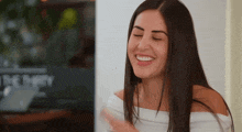 a woman in a white off the shoulder top smiles