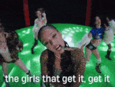 a group of girls are dancing on a green stage with the words " the girls that get it get it "