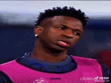 a soccer player is wearing a pink jersey and making a face .