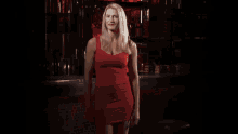 a woman in a black dress is dancing in a dark room with red lamps
