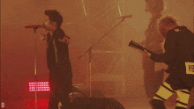 a man singing into a microphone next to a man playing a guitar