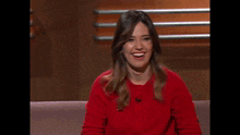 a woman in a red sweater makes a heart shape with her hands