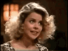 a woman with blonde hair is smiling and looking at the camera in a room .