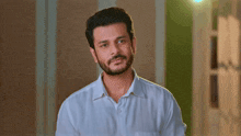 a man with a beard wearing a white shirt is looking at the camera