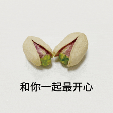 two pistachios cut in half on a white surface with chinese writing below them