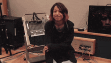 a woman sitting on the floor in front of a mixer with the letter d on the bottom right