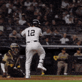 a baseball player with the number 12 on his back is about to swing his bat