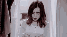 a woman is standing in a doorway reading a letter .