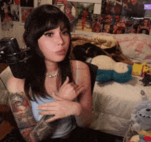 a woman with a tattoo on her arm is sitting in front of a microphone in a bedroom .