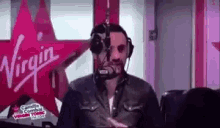 a man wearing headphones is standing in front of a microphone in a radio studio .