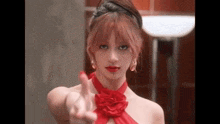 a woman in a red dress and red lipstick is giving a middle finger .