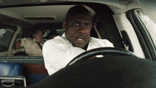 a man in a white shirt is sitting in a car with the word prime on the back seat