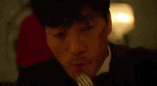 a man in a suit and tie is eating a fork .