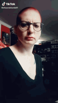 a woman with red hair wearing glasses and a black shirt has tiktok written on her face