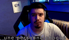 a man wearing headphones and a white shirt with the words une personne choque on the bottom