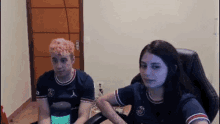 a man and a woman are sitting in front of a computer screen ..