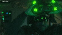 a man is wearing a helmet with green lights on it and the xtoms / 2005 logo is visible behind him