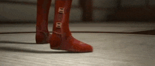 a person wearing a pair of red boots is standing on a tiled floor .