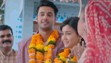 a man and a woman are standing next to each other with flowers around their necks