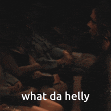 a woman in a black dress says " what da helly " in a dark room