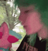 a person with green hair is drinking water from a bottle