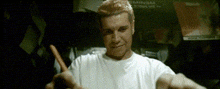a man in a white shirt is holding a carrot in his hands