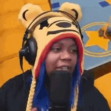 a woman wearing a winnie the pooh hat and headphones is speaking into a microphone .