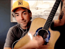 a man wearing a yellow hat that says arbor holds a guitar