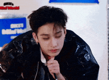a young man in a black leather jacket is holding a microphone in his hand .