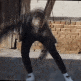 a person is standing in front of a brick wall wearing white shoes