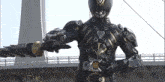 a man in a black and gold superhero costume is holding a sword in his hand .