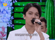 a man singing into a microphone with chinese writing on the screen