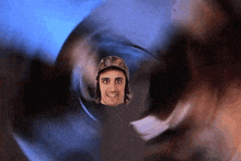 a man wearing a hat with the letter w on it is looking through a hole in a glass