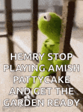 kermit the frog is sitting on a railing looking out a window with a quote on it .