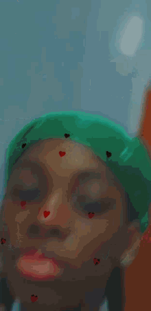 a girl wearing a green bandana and a blue shirt has red hearts on her face