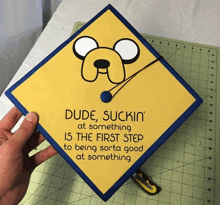 a person is holding a graduation cap that says dude suckin at something is the first step to being sorta good at something