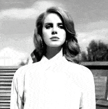 a black and white photo of a woman with long hair wearing a white shirt .