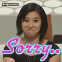 a woman is making a funny face and the word sorry is behind her .