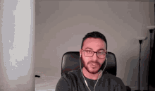 a man wearing glasses and headphones is sitting in a chair