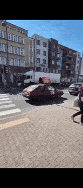 a red car is parked on the side of the road in front of a large building