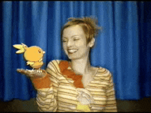 a woman in a striped shirt is holding a stuffed bird in her hand