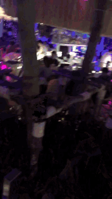 a group of people are sitting at tables in a dark room with purple lights