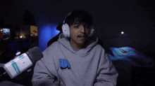 a man wearing headphones and a sweatshirt with the letter w on it is pointing